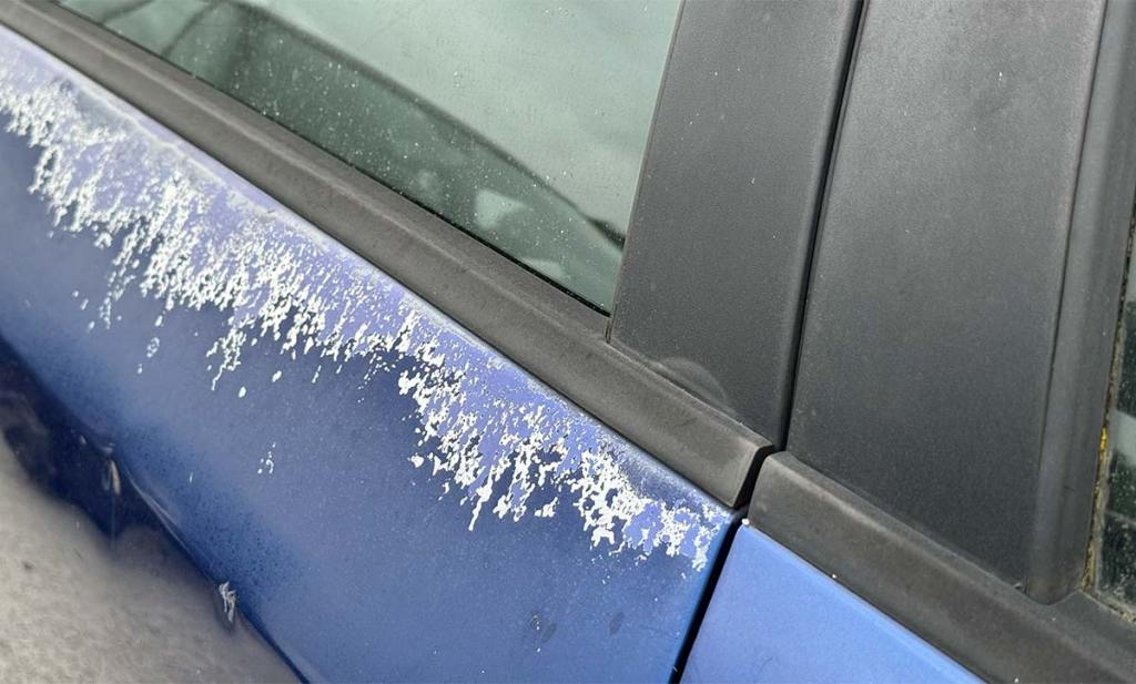 Vernis de carrosserie écaillé sur une portière de voiture bleue